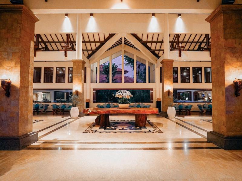 Hall d'hôtel élégant avec grande façade vitrée, espaces de sièges modernes et éclairage chaleureux