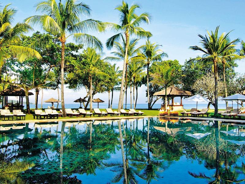 Large pool with pool bars and palm trees in tropical resort during daylight