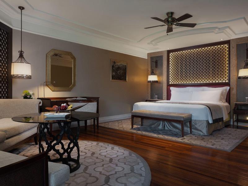 Elegant hotel room with large bed, sofa, and warm lighting design.