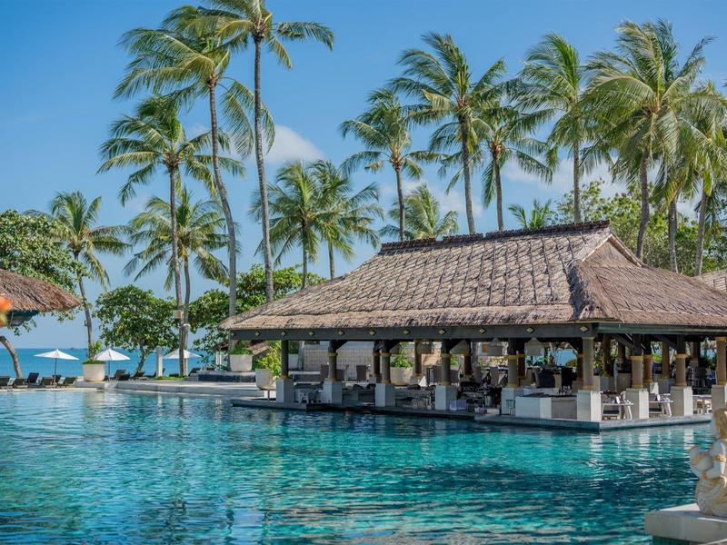Pool bar in tropical setting with palm trees and ocean view