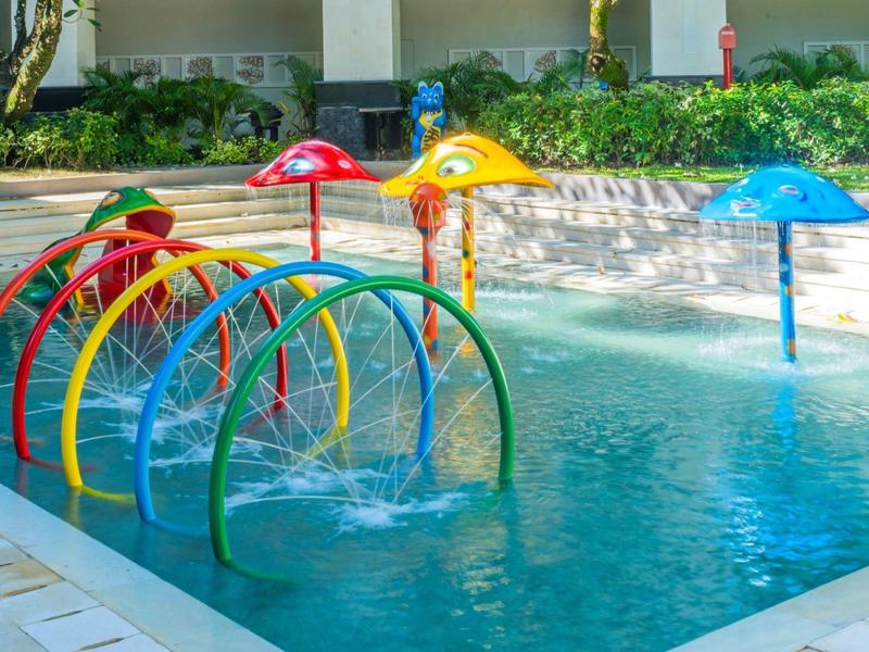 Colorful water play area with mushroom and rainbow arches in a hotel pool.