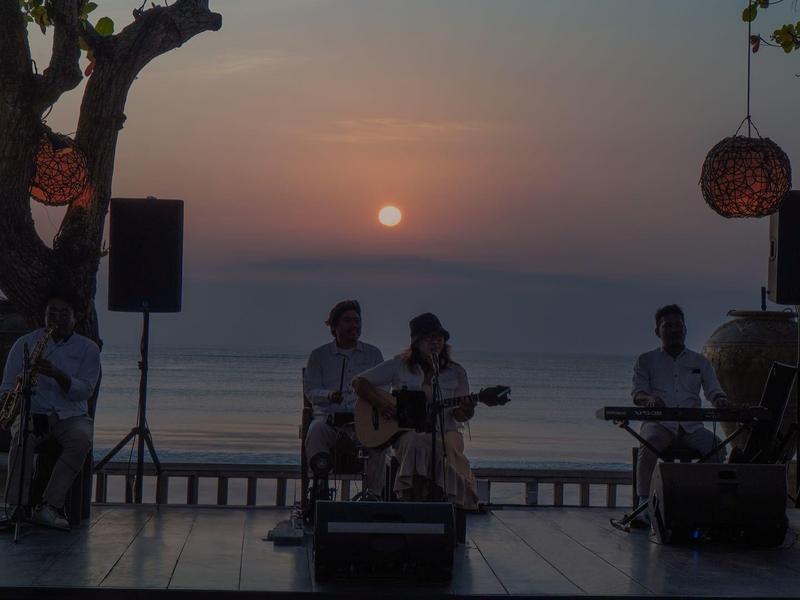 Band playing at sunset on a terrace overlooking the sea.