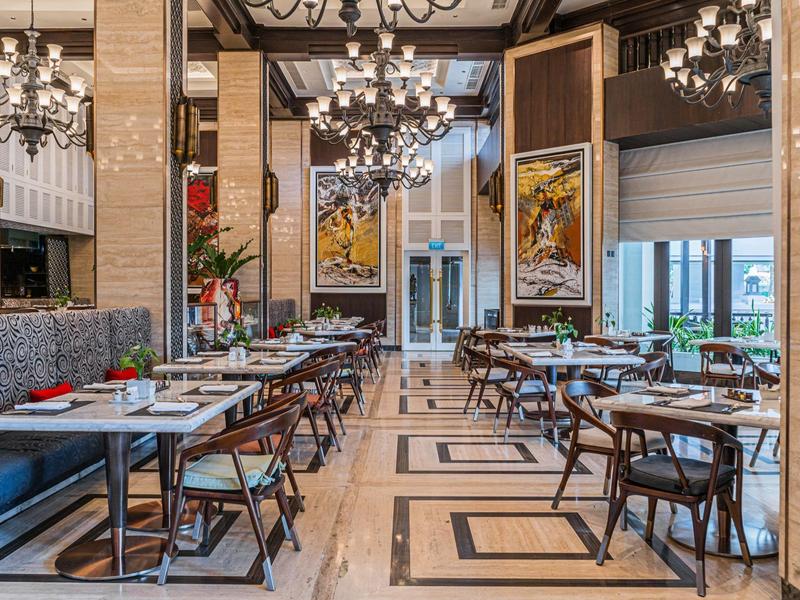 Elegant restaurant with modern wooden chairs, tables, and large chandeliers.