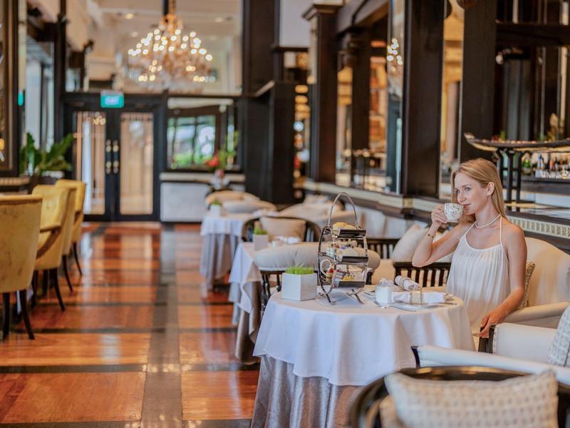 Elegant restaurant with stylishly set tables and a woman sitting at one table.