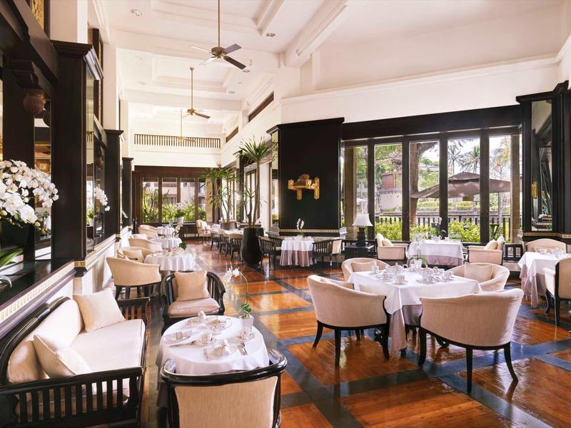 Elegant dining room with white tables and comfortable chairs in a hotel.