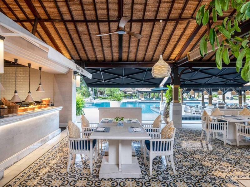 Open-air restaurant with set table, chairs, and view of water with boats.