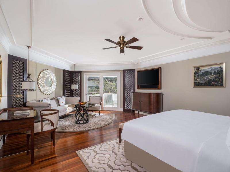 Elegant bedroom with large bed, ceiling fan, desk, TV, and terrace access.