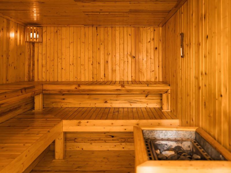 Wood sauna with tiered benches and heated stone stove for relaxing moments.