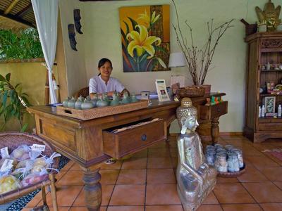 Ein Raum mit Holzschreibtisch, sitzender Frau, Metallfigur und Regalen mit Dekoration.