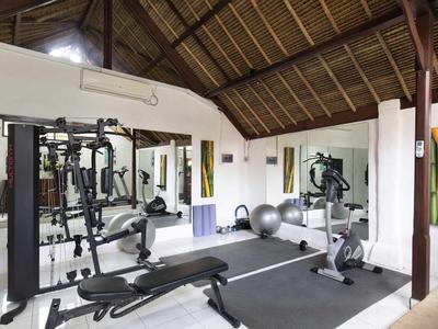 Moderner Fitnessraum mit Hantelbank, Trainingsgeräten und Gymnastikbällen unter Holzdach.