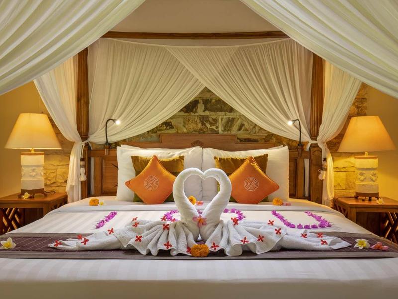 Gemütliches Doppelbett mit Baldachin, dekoriert mit Kissen, Blumen und zwei Tüchern in Herzform.