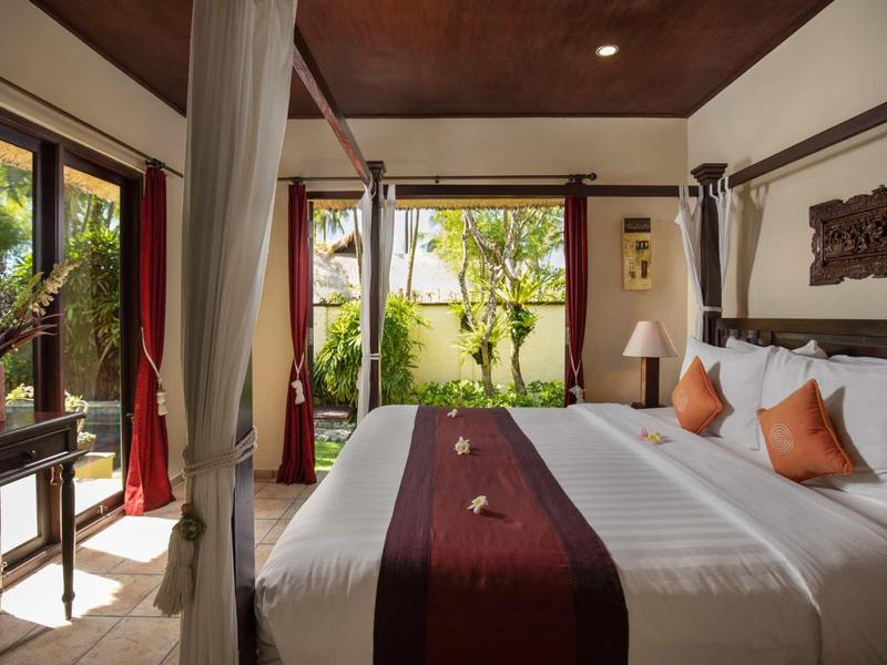 Schlafzimmer mit Himmelbett, weißen Wänden, braunen Holzmöbeln und Blick auf Garten mit viel Grün.