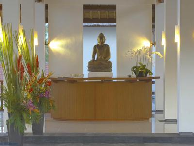 Nowoczesna recepcja z figurą Buddy, drewnianym kontuarem i dekoracjami kwiatowymi.