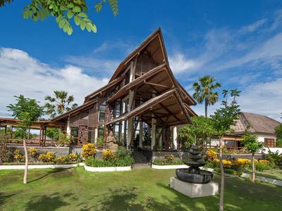 Nowoczesny budynek hotelu z drewnianym dachem i zadbanym ogrodem pod niebieskim niebem.