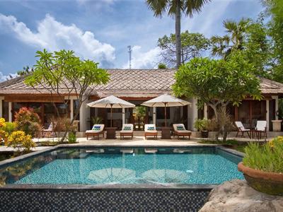 Accogliente casa vacanze con piscina, lettini e ombrelloni in ambiente tropicale.