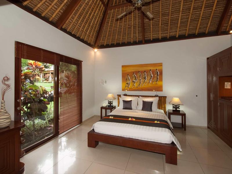 Nowoczesna sypialnia z dużym łóżkiem, drewnianymi meblami i wyjściem do ogrodu.