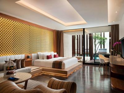 Elegant hotelkamer met groot bed, houten vloer en terras met planten.