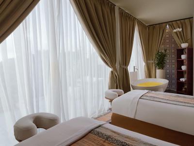 Lichte spa-kamer met massagetafels, gordijnen en grote spiegel.