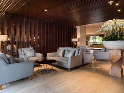 Modern ingerichte hotel lounge met grijze banken en decoratieve bloemstukken.