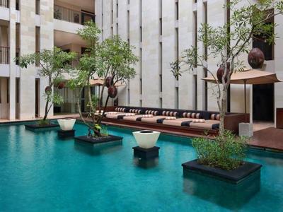 Binnenplaats met blauw zwembad, zitgedeelte en planten in een modern hotel.