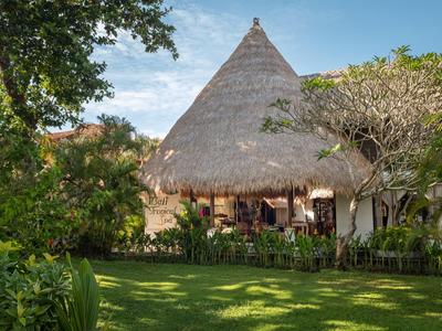 Casa con techo de paja rodeada de árboles verdes y césped en un paisaje soleado