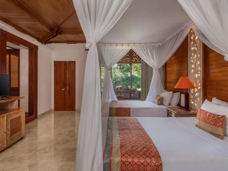 Chambre en bois accueillante avec deux lits à baldaquin, une TV et une grande fenêtre sur la verdure.