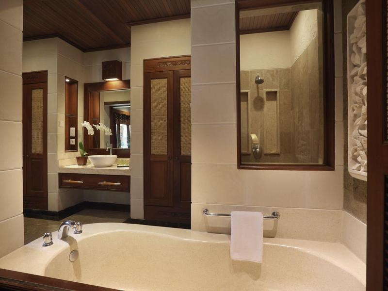 Salle de bain moderne avec baignoire, serviette sur porte-serviettes, portes en bois et lavabo avec miroir.