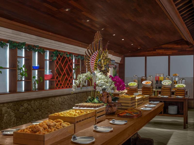 Table buffet avec pâtisseries, pain, fleurs et plats chauds dans une salle à manger.