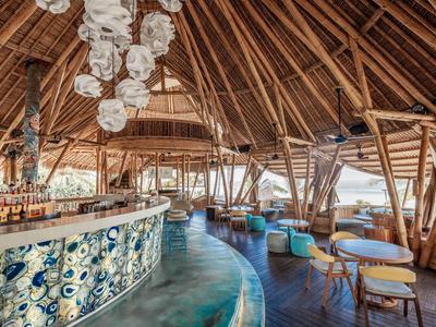 Barbereich mit Bambusstruktur, Sitzgelegenheiten und dekorativem Hängelicht in tropischem Ambiente