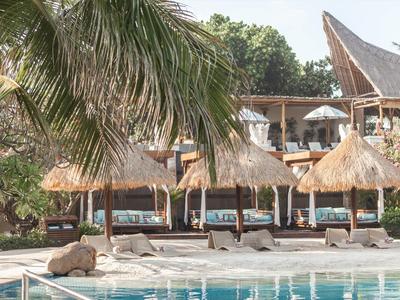 Luksusowy basen z leżakami, dachami krytymi strzechą i palmami w tropikalnym ośrodku.