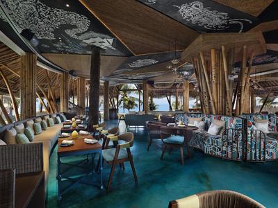 Interior de un restaurante tropical elegante con muebles coloridos y techos de madera.