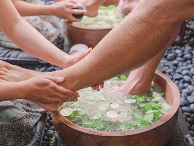Ludzie korzystają z masażu stóp z kąpielami ziołowymi w drewnianych miskach.
