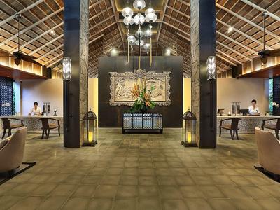 Przestronna lobby hotelowa z wysokim sufitem, recepcją i wygodnymi miejscami do siedzenia.