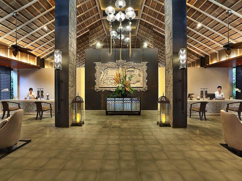 Przestronna lobby hotelowa z wysokim sufitem, recepcją i wygodnymi miejscami do siedzenia.