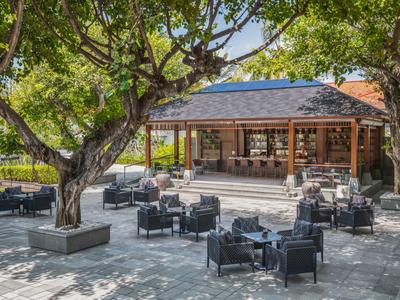 Area bar all'aperto con posti a sedere sotto grandi alberi e tettoia