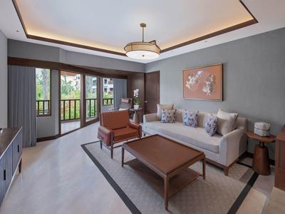 Moderně zařízený obývací pokoj se šedými stěnami, pohovkou, křesly a velkým oknem s výhledem do zeleně.