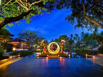 Scultura LOVE illuminata accanto a una piscina circondata da alberi e edifici di notte.