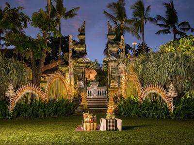 Portale balinese illuminato con palme e vegetazione verde di notte