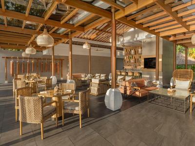 Area esterna coperta con tavoli e sedie in legno in un hotel.