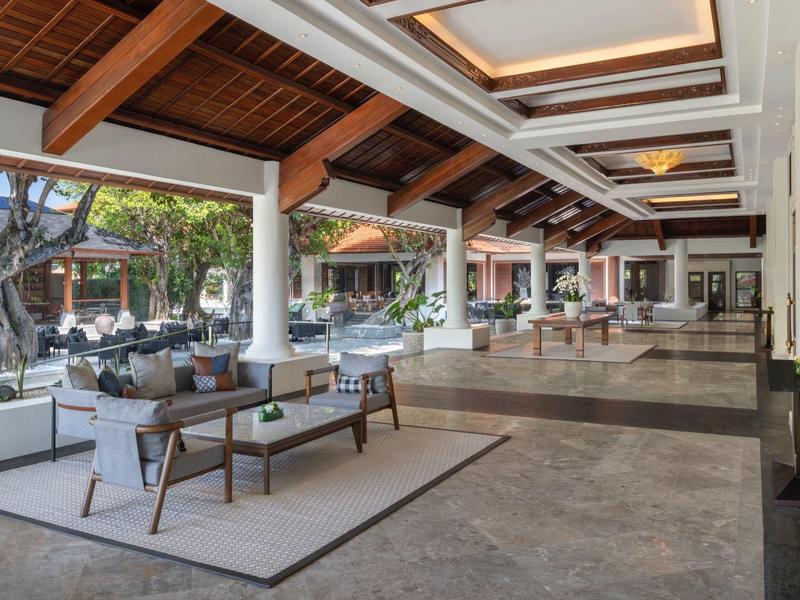 Otevřený lobby prostor hotelu se sezením, velkými okny a výhledem do venkovního prostoru.