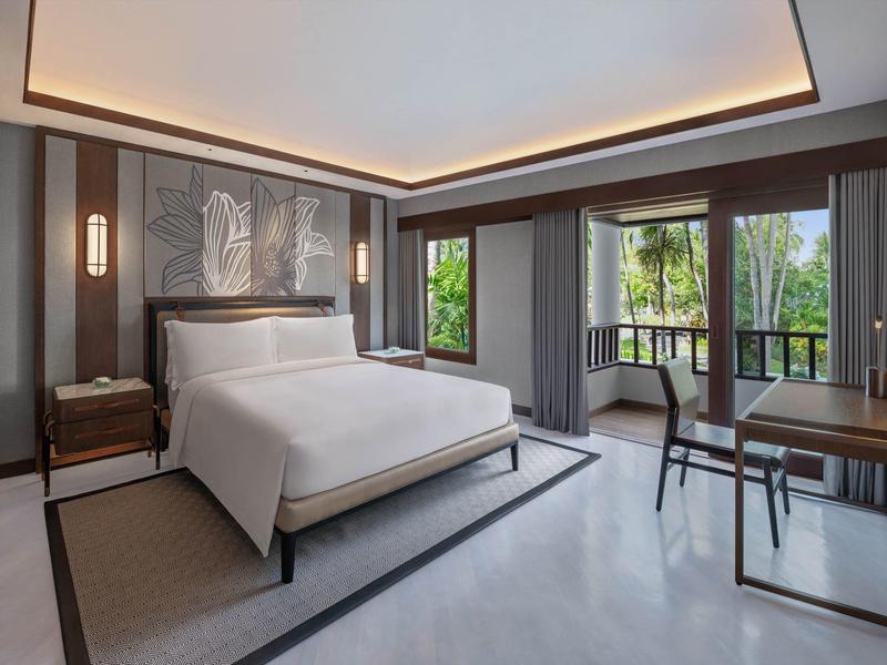 Moderní hotelový pokoj s manželskou postelí, balkónem s výhledem na zelené stromy a stylovým zařízením.