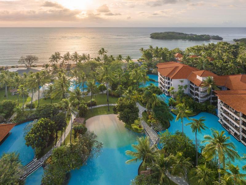 Luxusní resort s bazény, palmami a výhledem na oceán při západu slunce