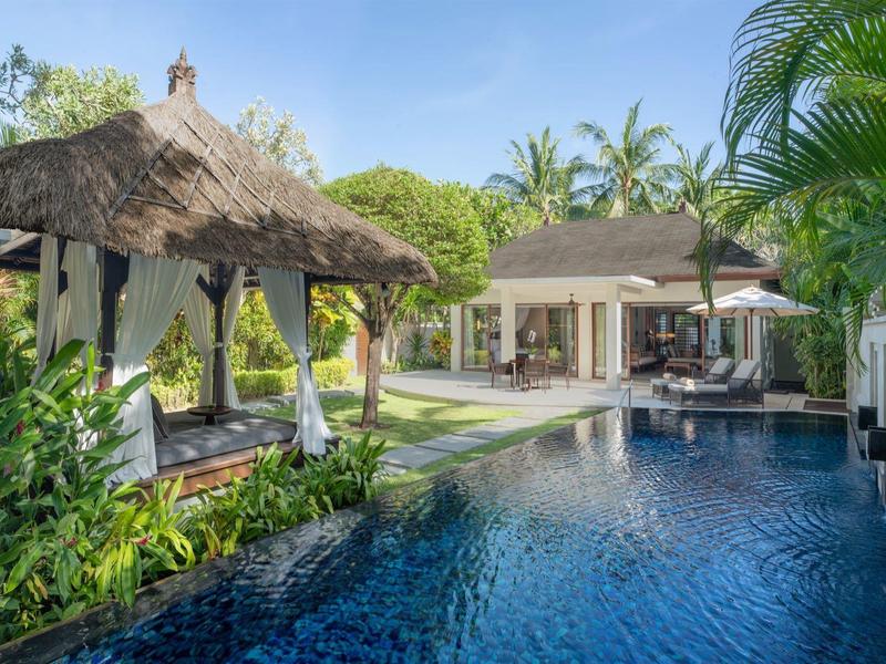 Luxusní vila s bazénem, pavilonem a tropickou zahradou pod jasnou oblohou.