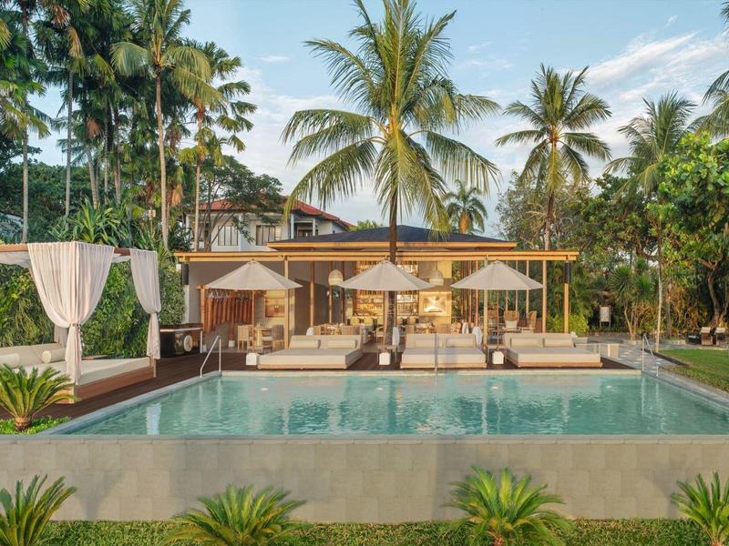 Luxusní bazén s lehátky a palmami v tropickém hotelu.