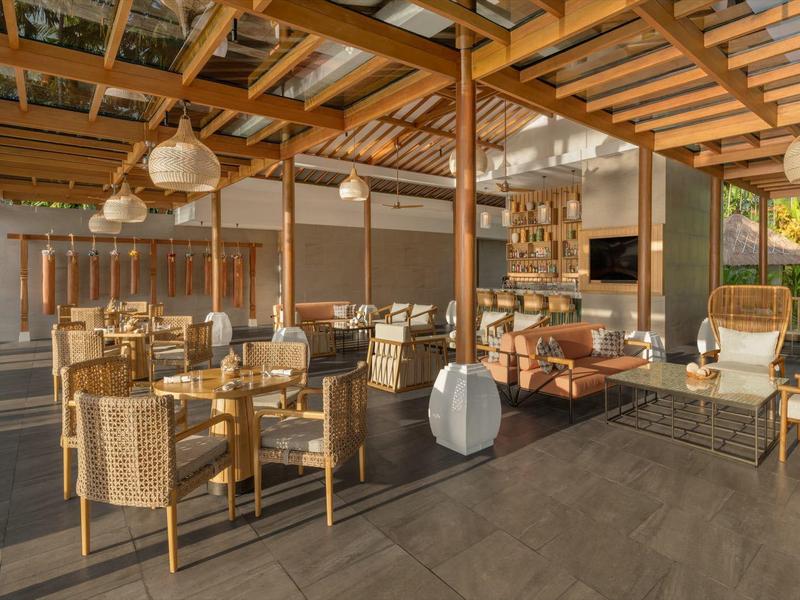 Otevřená, útulná posezení s proutěným nábytkem a dřevěnou střechou v exteriéru hotelu.