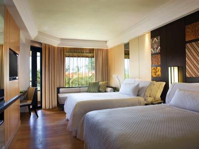 Habitación de hotel con dos camas, ventana grande, cortinas y televisor en la pared.