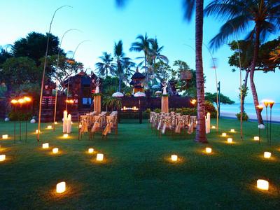 Ceremonia de boda al aire libre al atardecer con velas y palmeras en la playa.