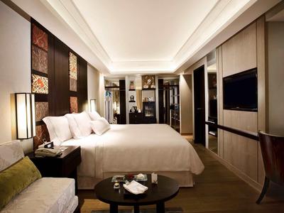 Habitación de hotel moderna con cama grande, área de estar y iluminación elegante.