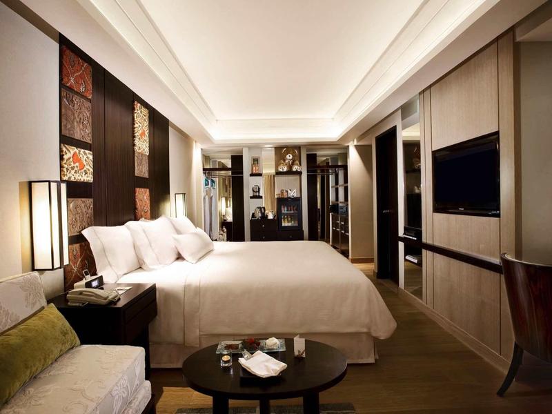 Habitación de hotel moderna con cama grande, área de estar y iluminación elegante.