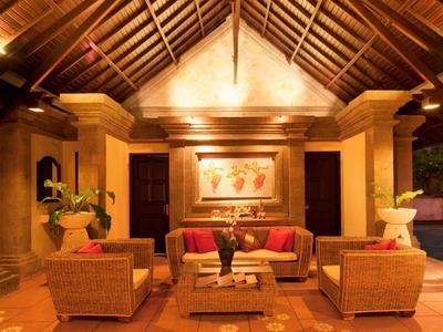 Pohodlná hotelová hala s dřevěným stropem a ratanovým nábytkem pod teplým osvětlením.